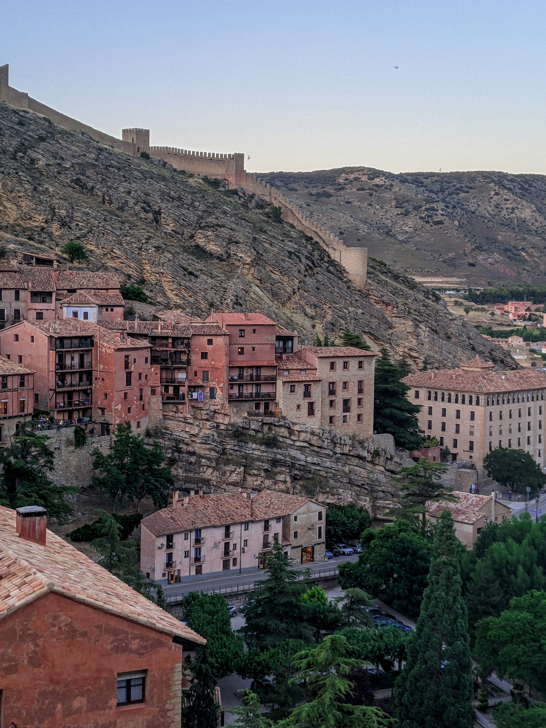 Pink rammed-earth houses in Albarracín set into the cliff below the town wall
