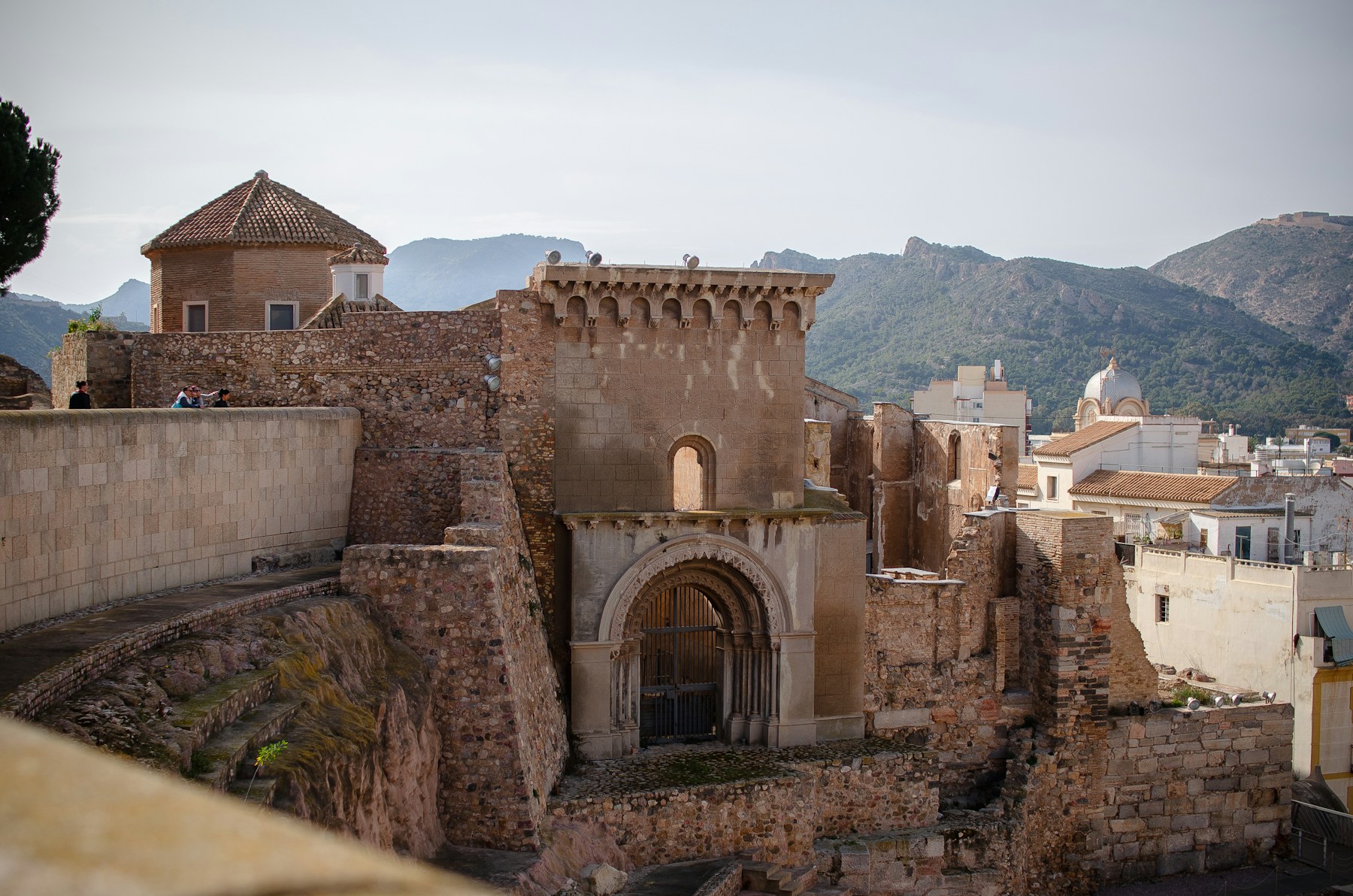 Stage front of the Roman theatre in Cartagena, with the old cathedral arch and the hills behind