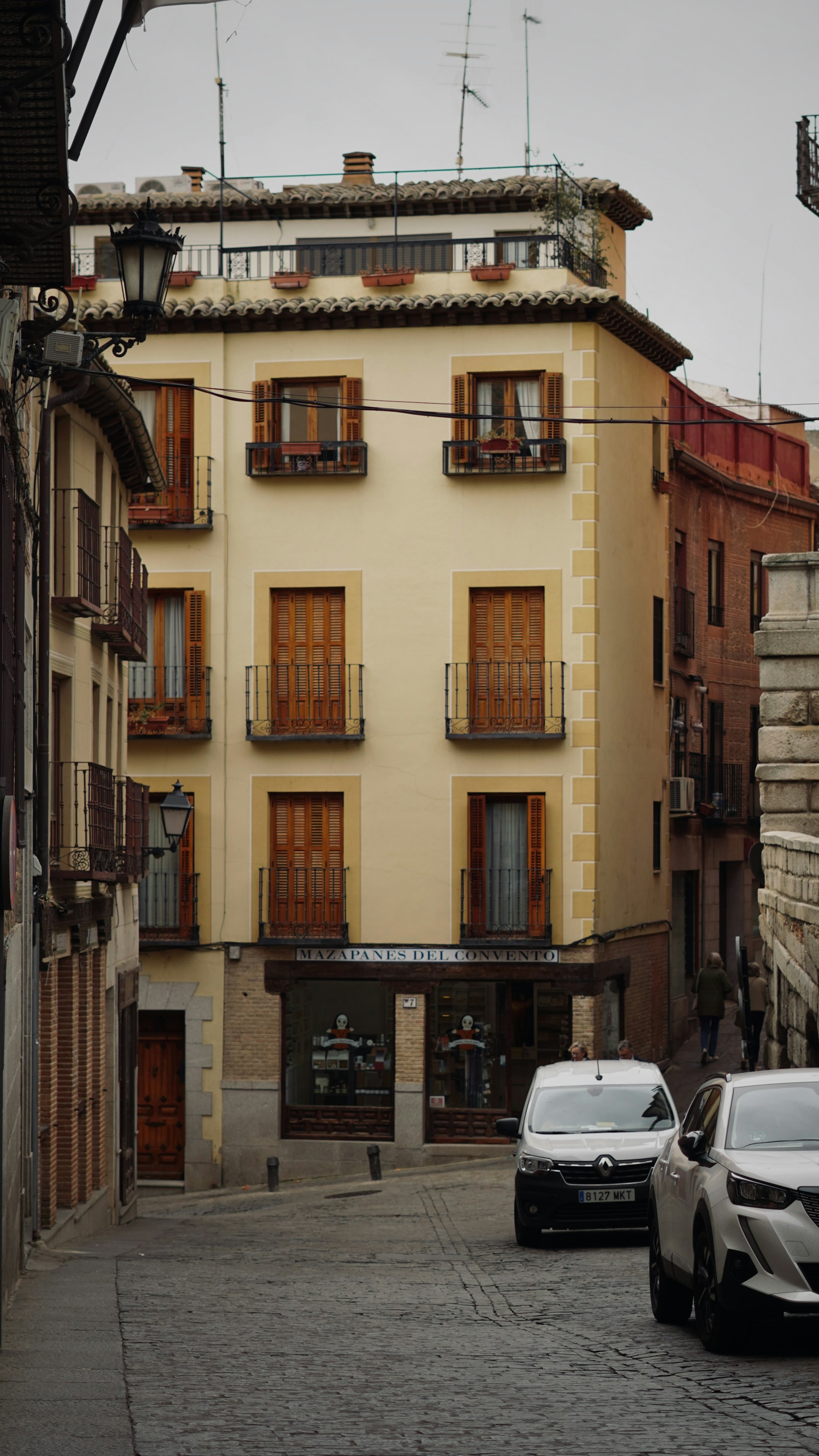 Calle adoquinada de Toledo con fachadas históricas y balcones